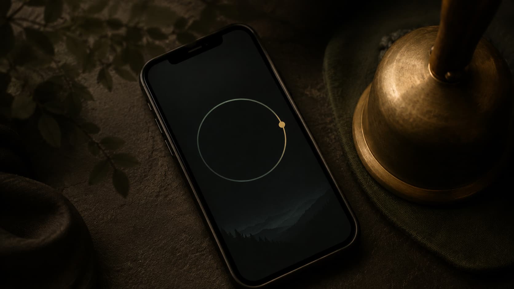 A phone showing a circular meditation timer beside a bell.